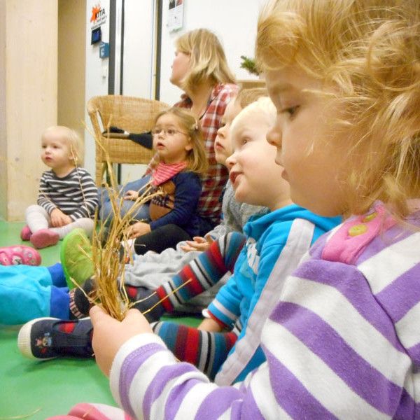 Kinder sitzen zusammen und hören zu, was gebastelt wird